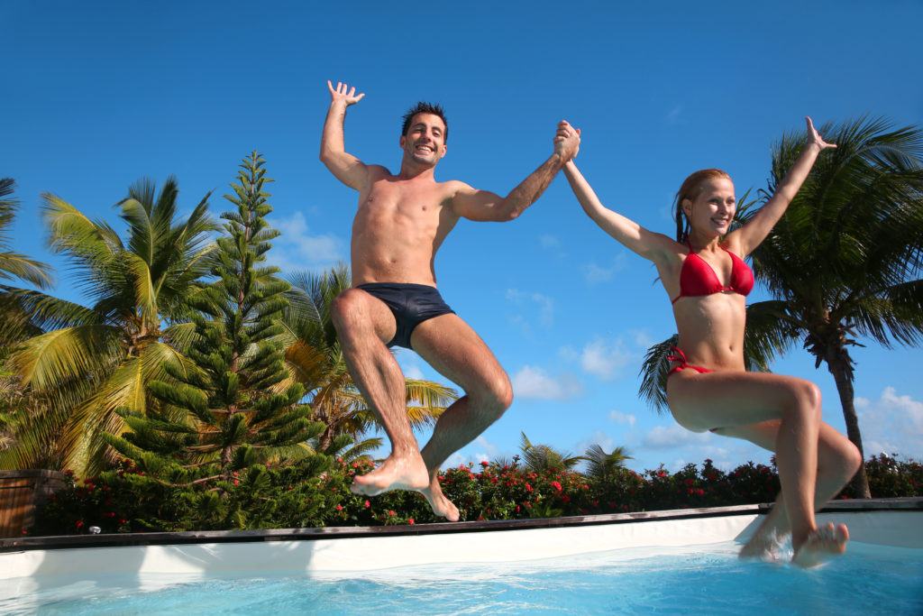 Young couple jumping in a modern plunge pool